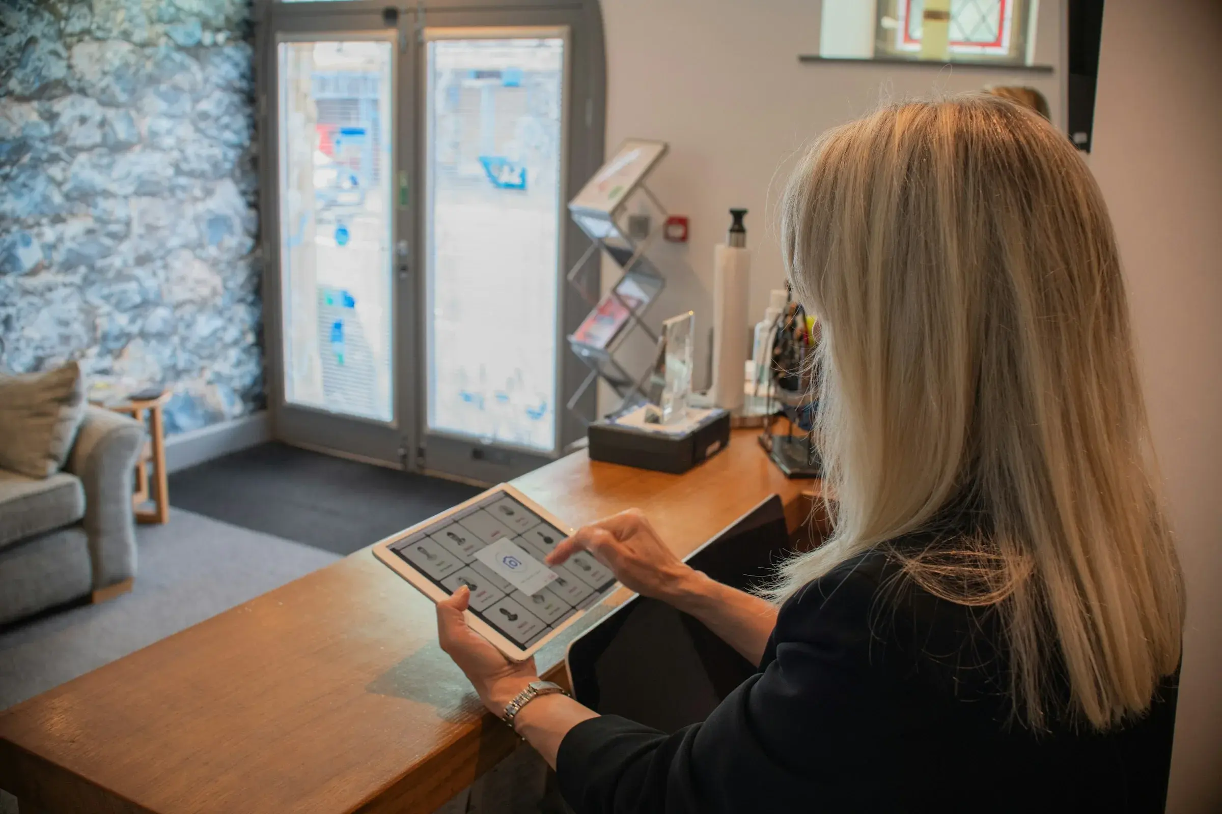 A receptionist using a tablet at a front desk